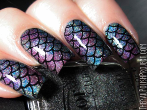 Unhas de Sereia- Pinterest. Foto mostra uma unha com esmalte roxo e azul com escamas de peixe em preto e brilho. Os dedos estão segurando um esmalte de cor preta brilhante
