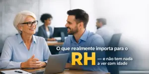Mulher idosa e homem jovem conversando em mesa com laptop sobre RH